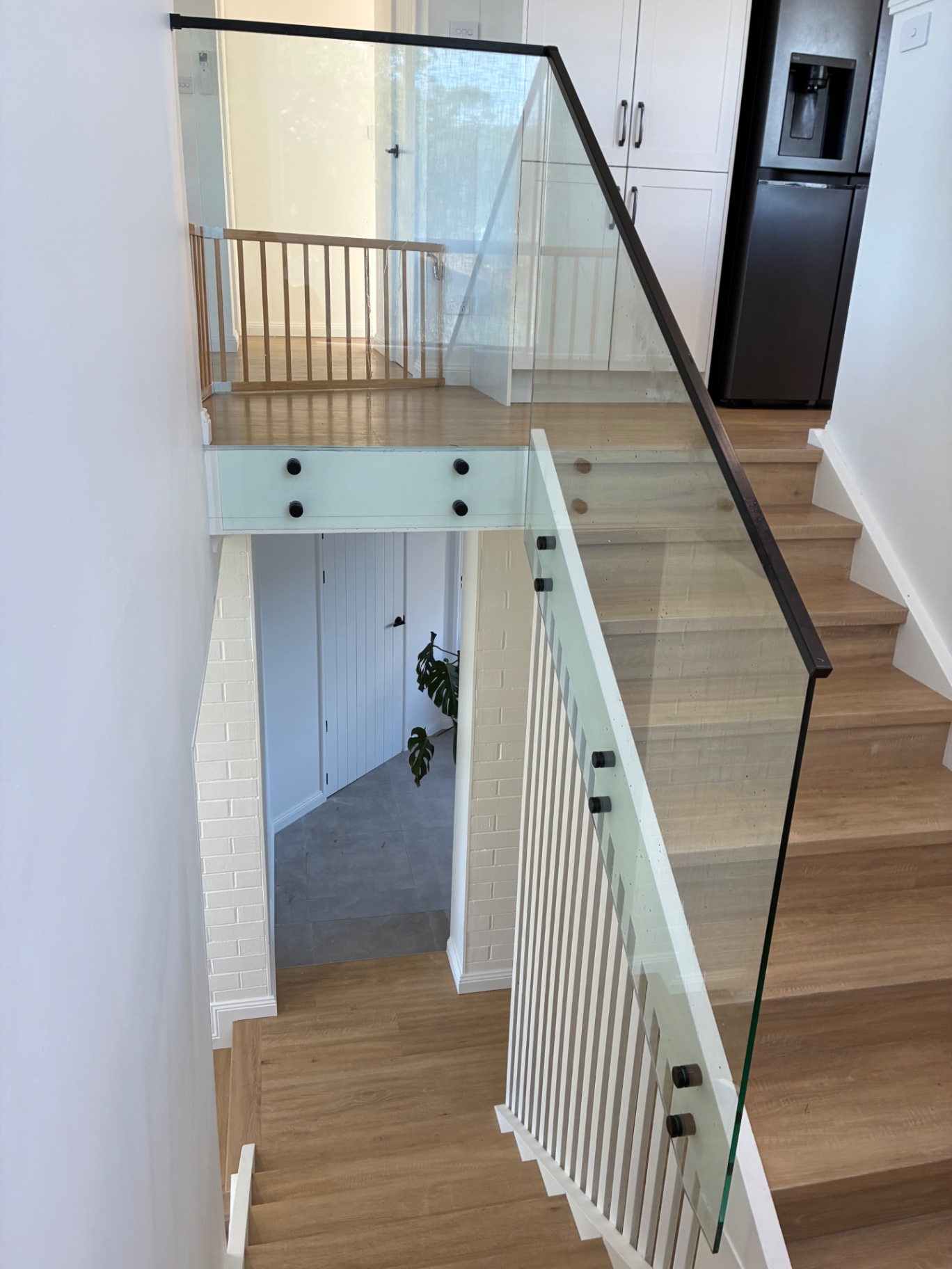 Internal glass balustrade with black hardware on timber-tread stairs