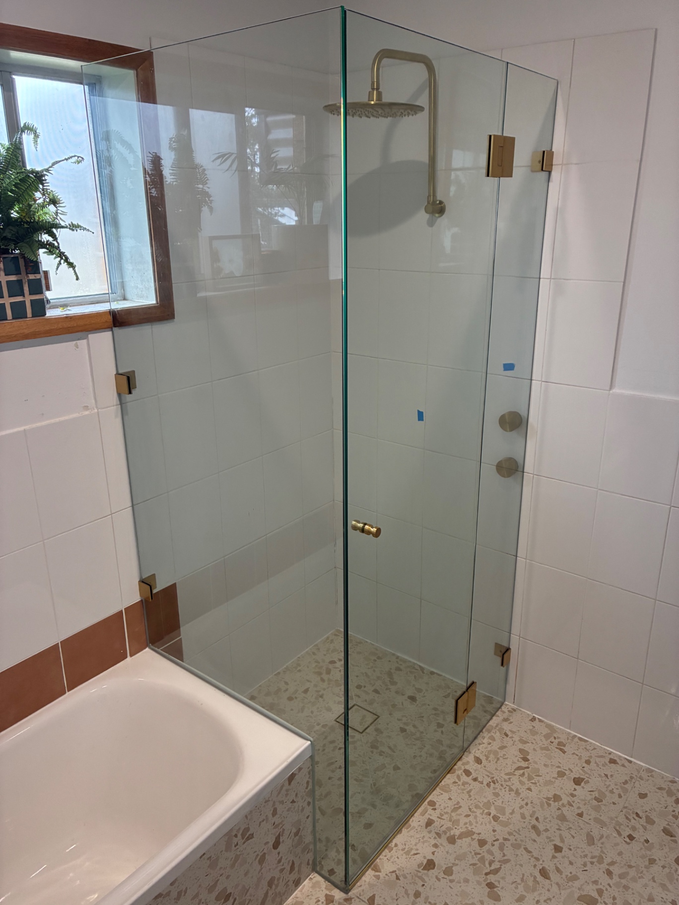 Frameless glass shower with gold hardware